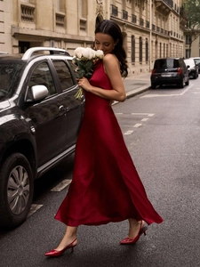 Outdoor shot of a red satin V-neck backless maxi dress with a flowing silk texture finish