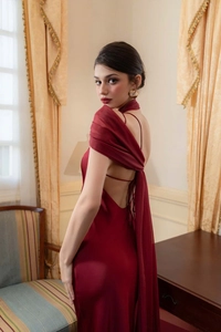 Detail of burgundy satin evening dress showing an open back with elegant lacing and cape