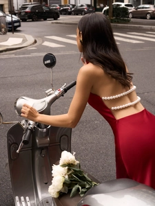 Detail of red satin dress featuring an open back design with elegant pearl chain accents