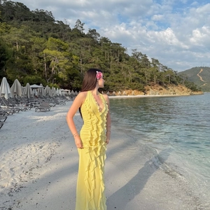 Detail of deep V-neckline and ruffles on a yellow backless maxi vacation dress