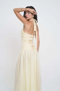 Detailed back view of cream halter maxi dress featuring lace-up design and pleated fabric