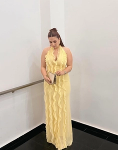 Detail of elegant pale yellow halter dress featuring vertical ruffles and a backless design