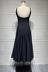 Detail of elegant black midi dress featuring a slim waist and pleated flowing hemline