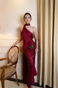 Détail macro de la robe de soirée en satin rouge vin montrant le drapé et la texture du tissu