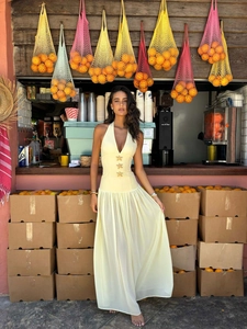 Detail of yellow halter maxi dress with gold starfish buckles and pleated fabric texture