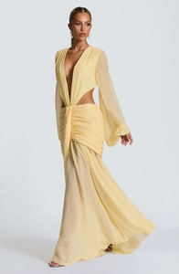 Dettaglio di abito lungo in chiffon giallo pallido con ritagli in vita e nodo drappeggiato