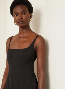Detail of black corset dress featuring vertical quilted stitching and a square neckline