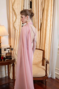 Pink satin evening gown featuring an elegant one-shoulder cape and open back design