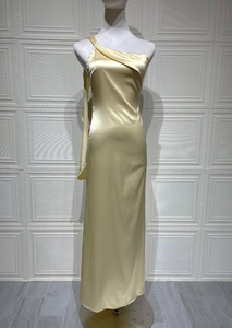 Détail de la robe en satin champagne montrant l'encolure asymétrique et le tissu plissé