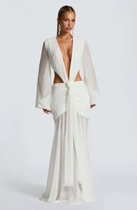 Dettaglio di un abito lungo in chiffon bianco con tagli in vita e gonna a pieghe