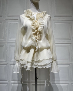 Détails des fleurs en 3D et des ourlets à volants sur la blouse en mousseline crème