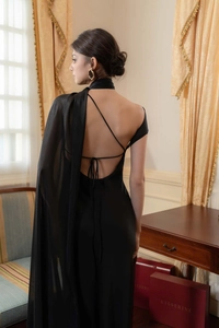 Detail of elegant black satin evening dress showing backless cross ties and cape sleeve