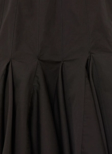 Detailed close-up of vertical seams and waist pleats on a black A-line dress