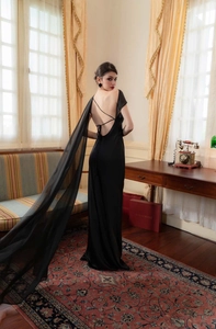Detailed back view of a slim satin gown featuring cross-strap back and a long tulle cape
