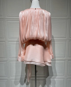 Detail view of pink satin pleated dress with glossy texture and double layer ruffle hem