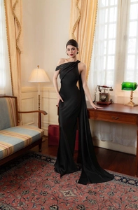 Detail of elegant one-shoulder black satin gown with pleats and a long floor-length sash