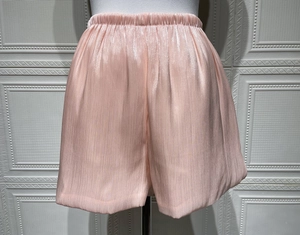 Detail of light pink elastic waist shorts with pleated texture and pearl satin finish