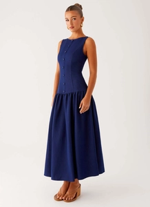 Detail view of the pleated drop waist and single-breasted buttons on a navy maxi dress