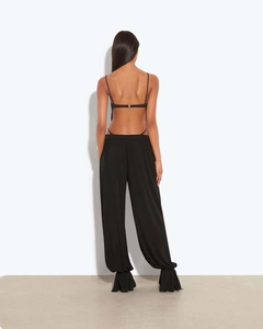 Détail du haut dos nu noir et du pantalon large à taille haute avec un drapé élégant