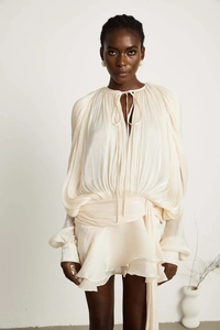 Close-up of cream pleated puff sleeve dress with delicate tie-up cutout neckline detail