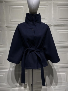 Detailed close-up of dark blue wool-like cape coat featuring high collar and button accents
