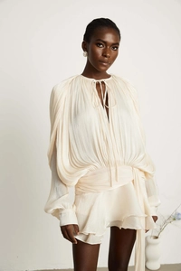 Detail of cream pleated dress fabric texture with wrap waist tie and subtle pearl sheen