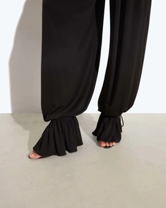 Détail d'une combinaison noire avec ourlet élastique à volants et style pantalon lanterne