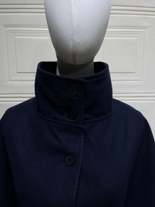 Detail view of the high stand collar and round black buttons on wool blend coat