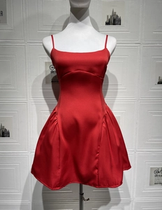 Detail of red satin mini dress featuring thin spaghetti straps and ruched pleated skirt sides