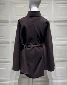 Detail of dark brown wool cape coat featuring a high collar and cinched waist belt