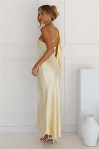 Détail de la robe élégante en satin jaune pâle avec épaule à volants et fente latérale