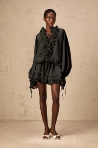 Détail de la fleur 3D sur le col et des manches à volants de cette robe noire chic