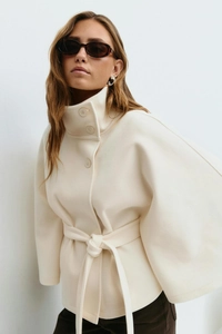 Detail of high collar buttons and waist belt texture on white wool blend cloak coat