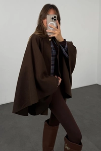 Detail of dark brown wool blend poncho with a decorative gold button over a checkered shirt