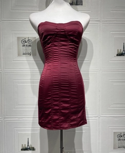 Detail of burgundy corset dress with vertical boning and sleek satin fabric on mannequin