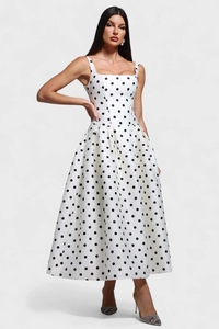 Gros plan d'une robe mi-longue vintage blanche à pois noirs avec un ourlet évasé élégant
