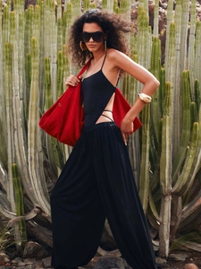 Combinaison noire dos nu sexy avec pantalon large et un grand sac à main rouge chic