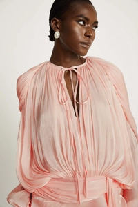 Detail of pink pleated bubble sleeve dress featuring shimmering fabric and neck-tie design