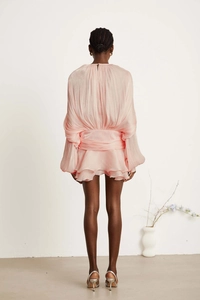 Detail view of pink pleated puff sleeve dress featuring back tiered ruffles and belted waist