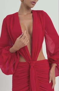 Dettaglio macro dell'abito lungo rosso in chiffon con scollo a V e ritagli in vita