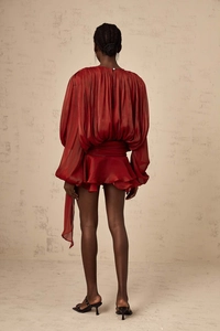 Detail view of deep red pleated long sleeve blouse and ruffled skirt set back silhouette