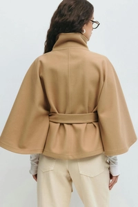 Back view of a camel wool cape coat featuring a high neck and adjustable tie waist belt