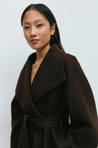 Detailed texture of thick dark brown wool coat with lapel collar and slim waist belt