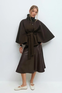 Detail view of a brown wool poncho coat with buttons and matching leather midi skirt