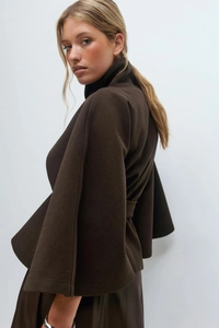 Detail view of high collar and oversized bell sleeves on a wool blend poncho coat