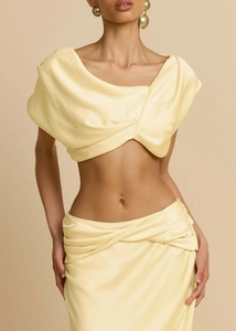 Detail eines hellgelben Satin-Zweiteilers mit drapiertem Crop-Top und Faltenrock für Damen
