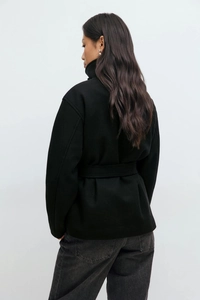 Detail view of the black wool blend jacket with stand collar and waist-tie belt