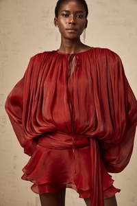 Detail of dark red pleated dress with puff sleeves and tie-up neck in silk texture