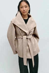Detail of oatmeal wool coat featuring large lapels and adjustable waist belt tie