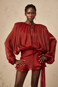 Detail of rust red pleated dress showing metallic silk texture and puff sleeves